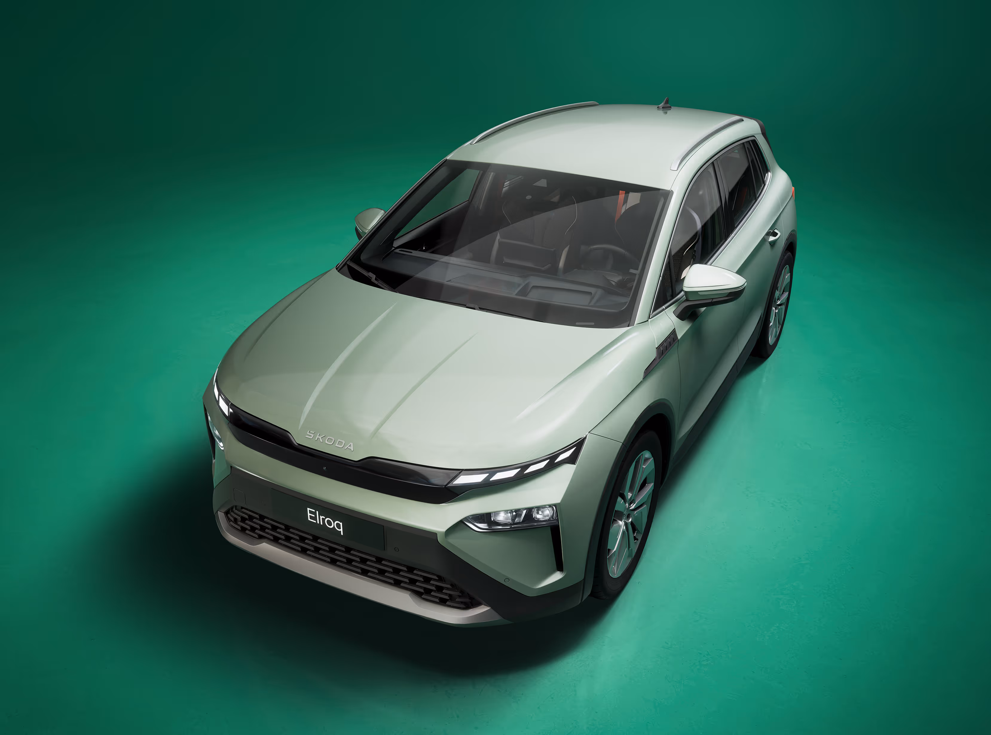 Vogelperspektive auf einen Škoda Elroq in der Farbe Timiano-Grün vor einem grünen Studiohintergrund. Die Dachlinie und Proportionen des Fahrzeugs sind gut erkennbar.