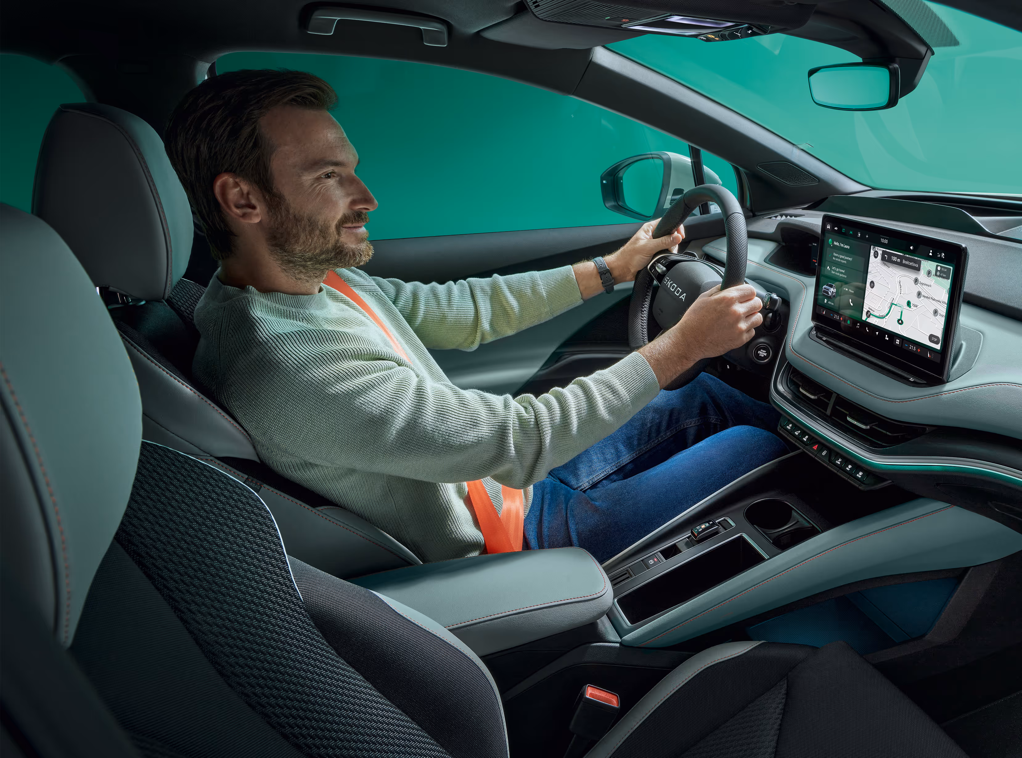 Ein Mann sitzt auf dem Fahrersitz eines Škoda Elroq, beide Hände am Lenkrad. Er schaut auf den freistehenden 13-Zoll-Infotainmentbildschirm.