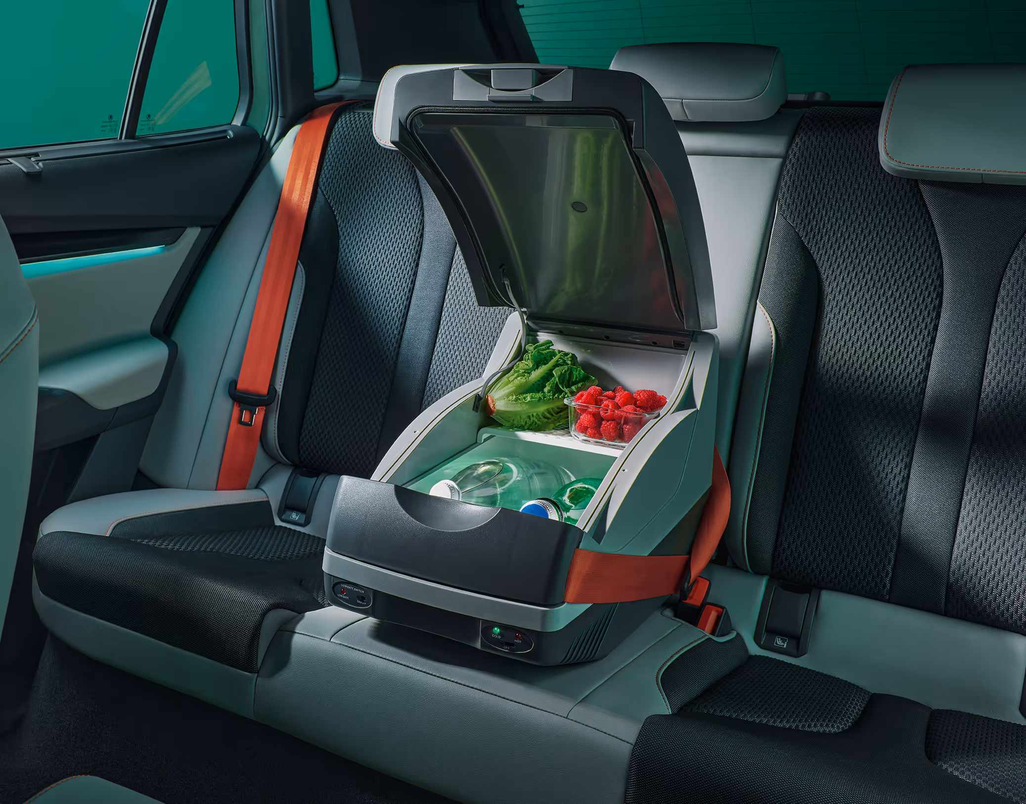 Eine Kühlbox, die mit dem Sicherheitsgurt auf dem mittleren Rücksitz des Škoda Elroq befestigt ist. Die Box ist geöffnet und mit Lebensmitteln gefüllt.