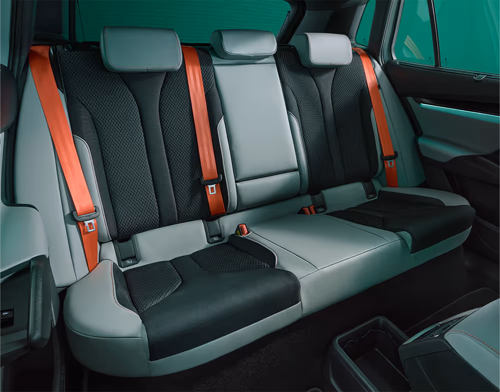 Blick auf die Rücksitzbank des Škoda Elroq. Die Aufnahme deutet eine großzügige Kopf- und Beinfreiheit an. Die roten Sicherheitsgurte setzen einen farblichen Akzent.
