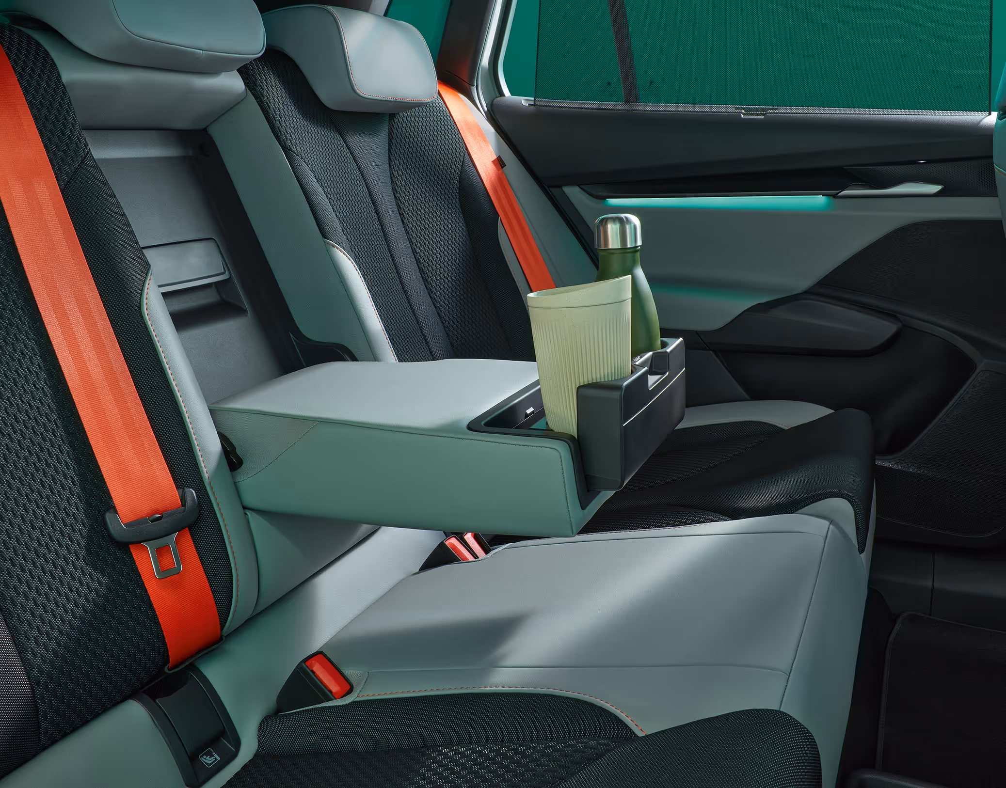 Die ausklappbare Mittelarmlehne im Fond des Škoda Elroq. Im integrierten Getränkehalter stehen eine dunkelgrüne Thermosflasche und ein hellgrüner Becher.