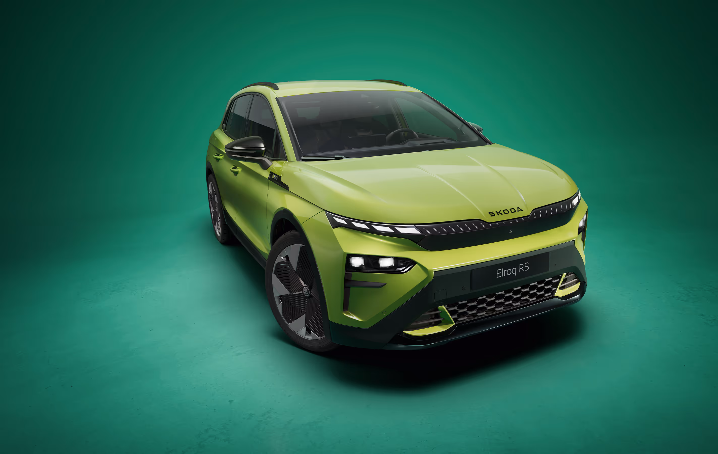 Frontalansicht des Škoda Elroq RS in der Farbe Mamba-Grün vor grünem Studiohintergrund. Das RS-Modell zeigt ein noch aggressiveres Design mit spezifischen Stoßfängern und schwarzen Details.