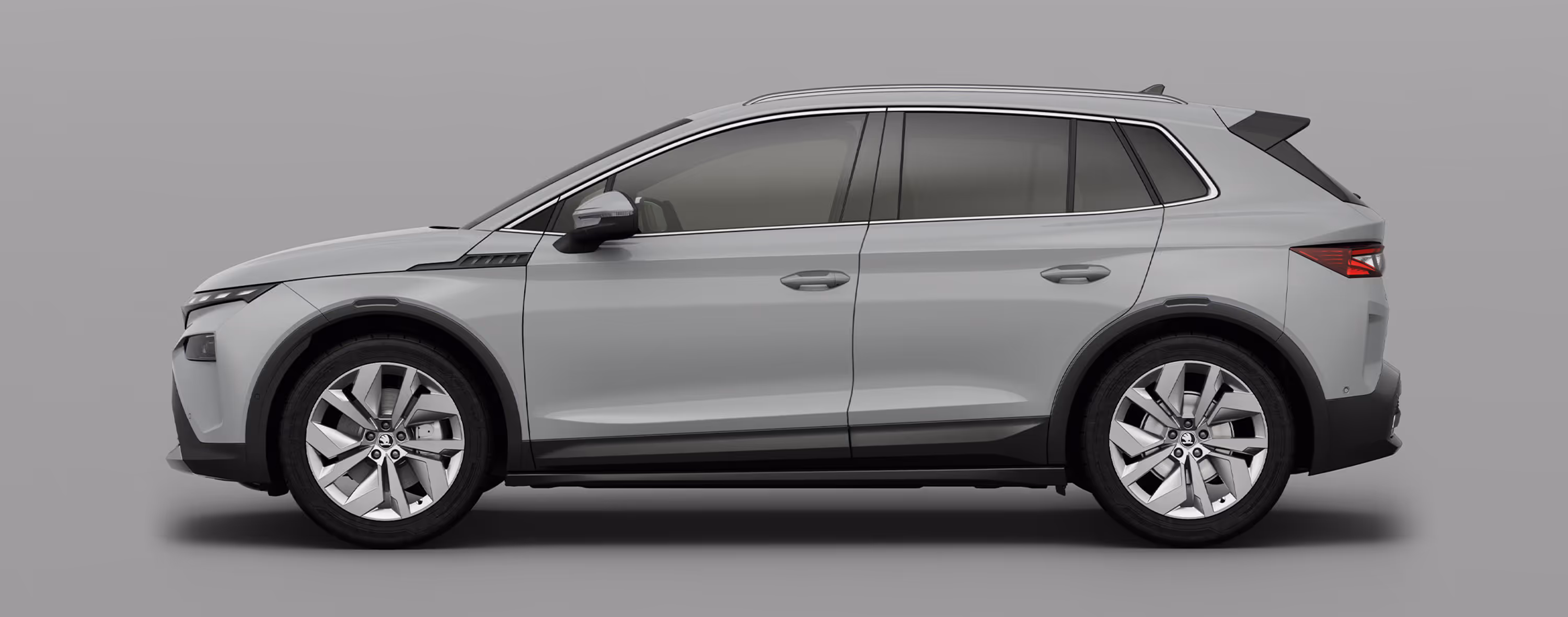 Seitenansicht eines Škoda Elroq in der Farbe Stahl-Grau mit 20 Zoll Leichtmetallfelgen “Vega” vor einem einfarbigen Hintergrund im Farbton der Fahrzeuglackierung.
