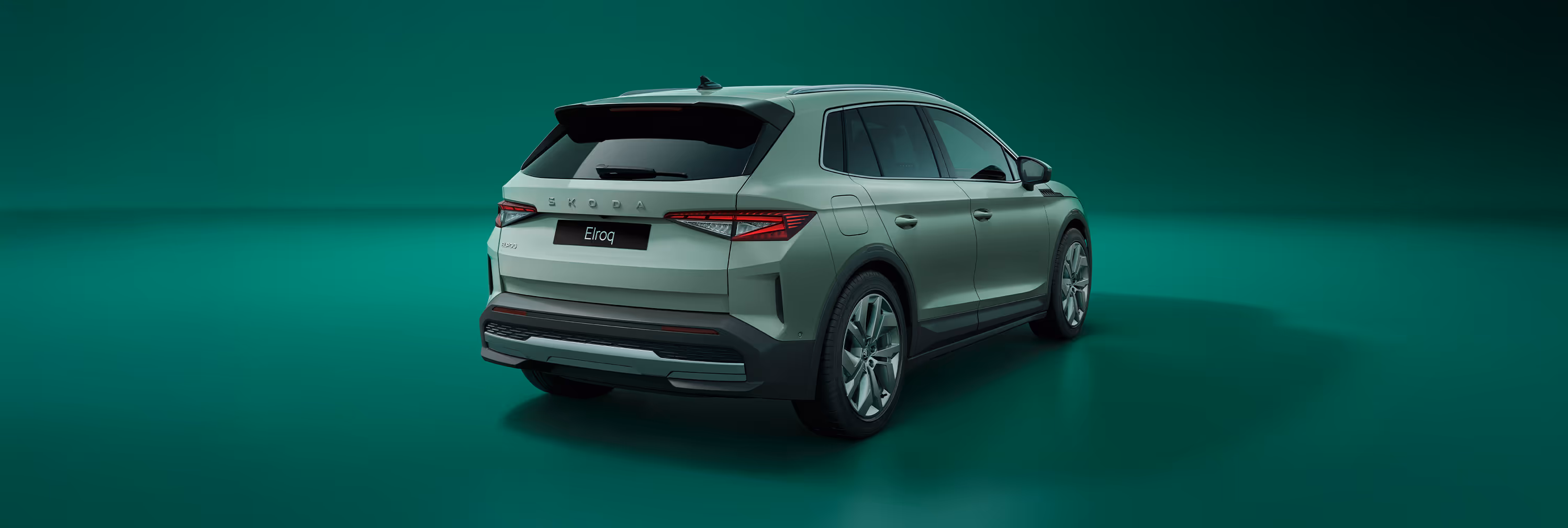 Schräge Heckansicht eines Škoda Elroq in der Farbe Timiano-Grün vor einem grünem Studiohintergrund. Die Rückleuchten und der prominente Škoda Schriftzug am Heck sind deutlich zu sehen.