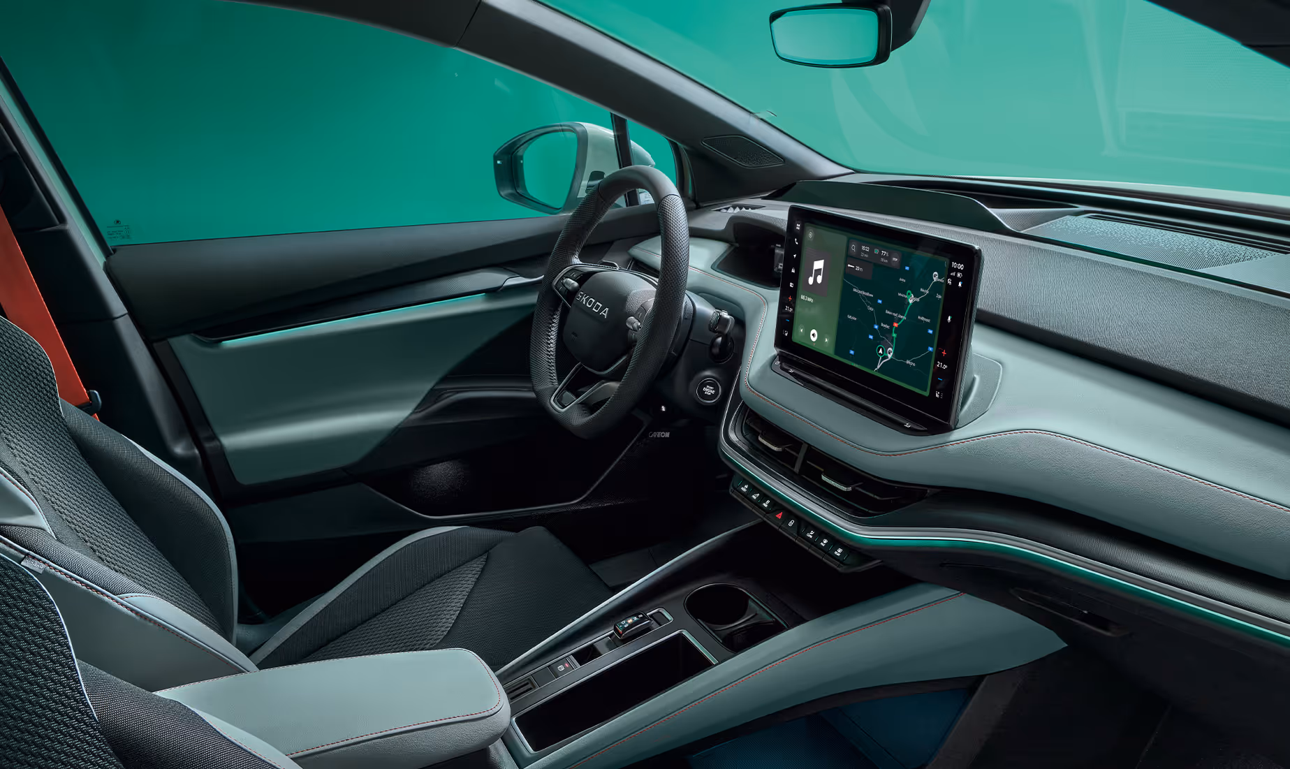 Das Cockpit des Škoda Elroq mit Blick auf das Lenkrad und den freistehenden 13-Zoll-Infotainmentbildschirm. Die grüne Ambientebeleuchtung setzt einen farbigen Akzent entlang des Armaturenbretts und der Türen.