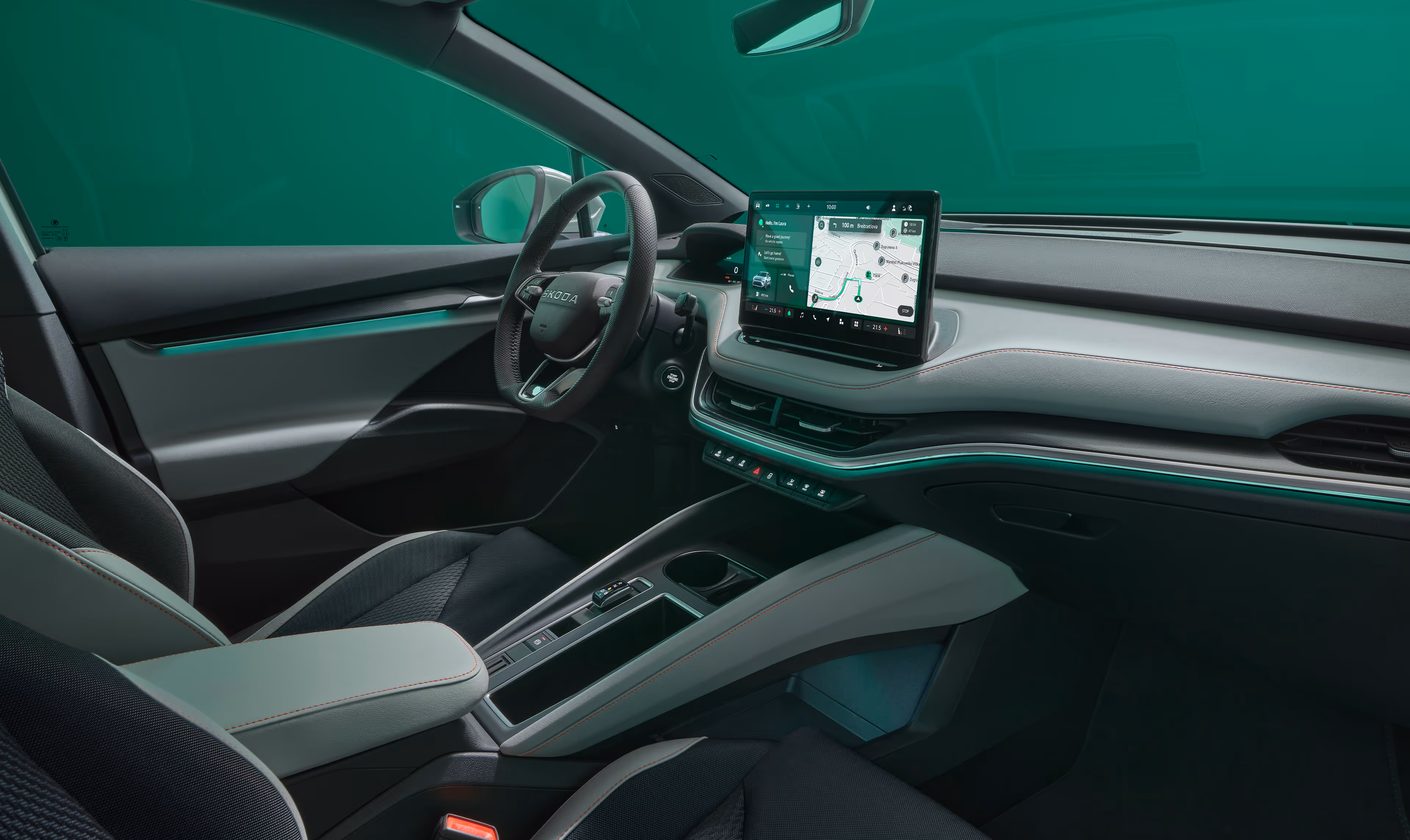 Das Cockpit des Škoda Elroq mit Blick auf das Lenkrad und den freistehenden 13-Zoll-Infotainmentbildschirm. Die grüne Ambientebeleuchtung setzt einen farbigen Akzent entlang des Armaturenbretts und der Türen.