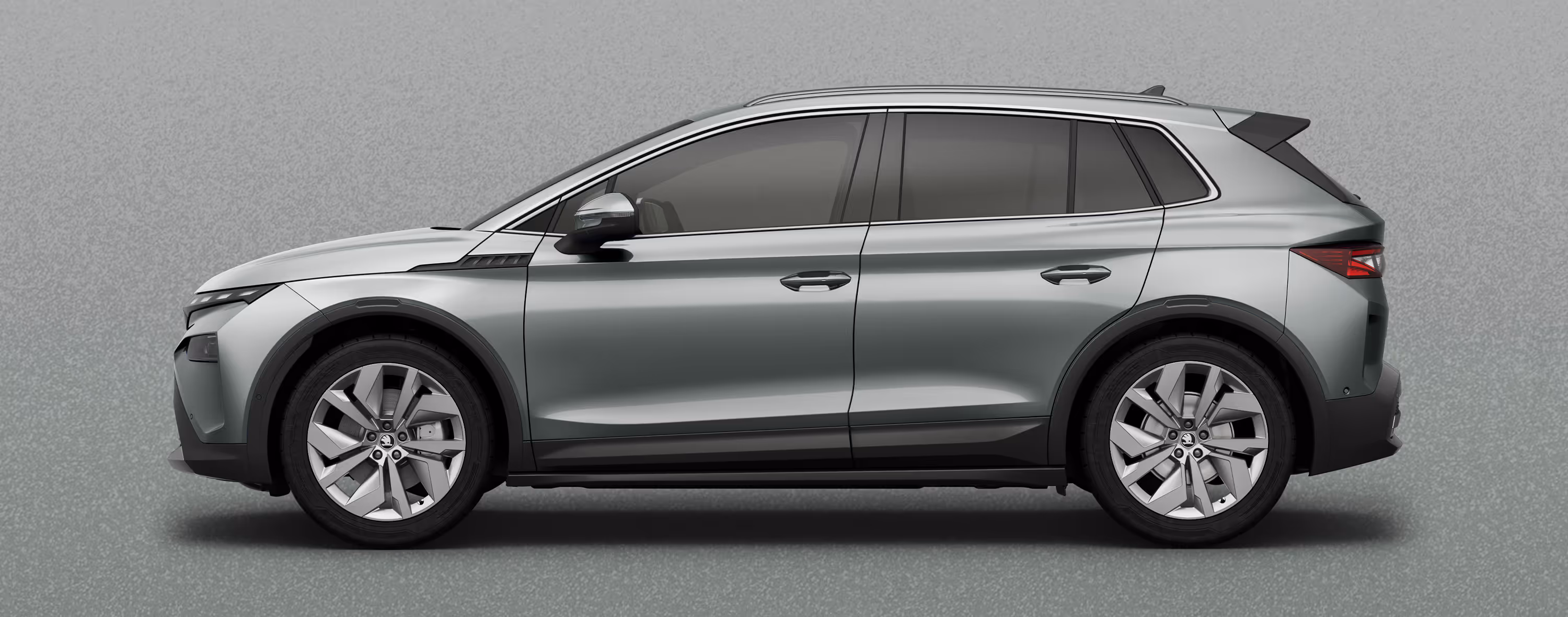 Seitenansicht eines Škoda Elroq in der Farbe Stahl-Grau mit 20 Zoll Leichtmetallfelgen “Vega” vor einem einfarbigen Hintergrund im Farbton der Fahrzeuglackierung.