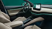 Ein Blick in den vorderen Innenraum des Škoda Elroq mit Fokus auf den Fahrer- und Beifahrersitz. Die Sitze der Design Selection „L&K“ sind mit beigem Leder bezogen und weisen cognacfarbene Ziernähte auf. Die grüne Ambientebeleuchtung leuchtet entlang des Armaturenbretts und der Fahrertür.