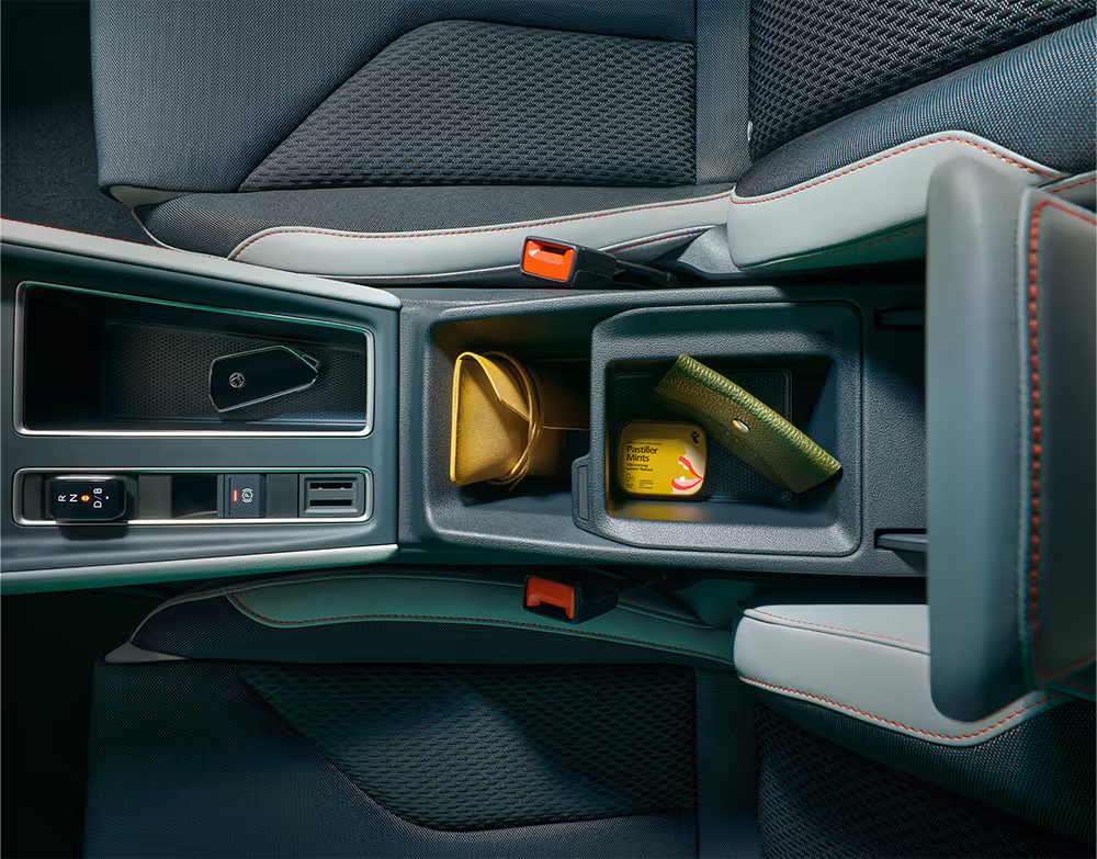 Blick von oben in die geöffnete Mittelarmlehne mit Ablagefach. Darin befinden sich eine Geldbörse, ein Schlüssel sowie eine kleine Schatulle.