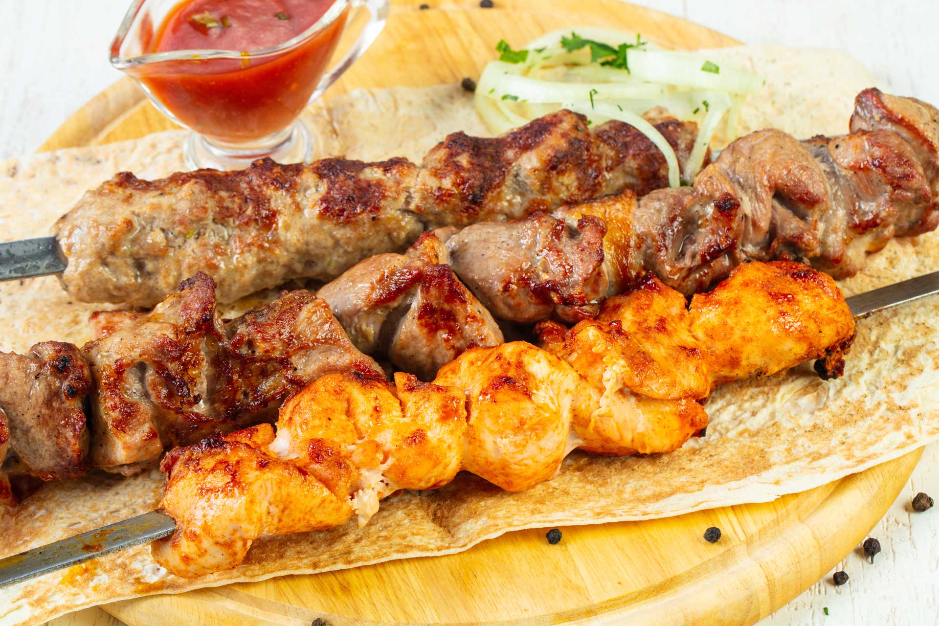 A plate of meat and vegetables with a side of sauce.