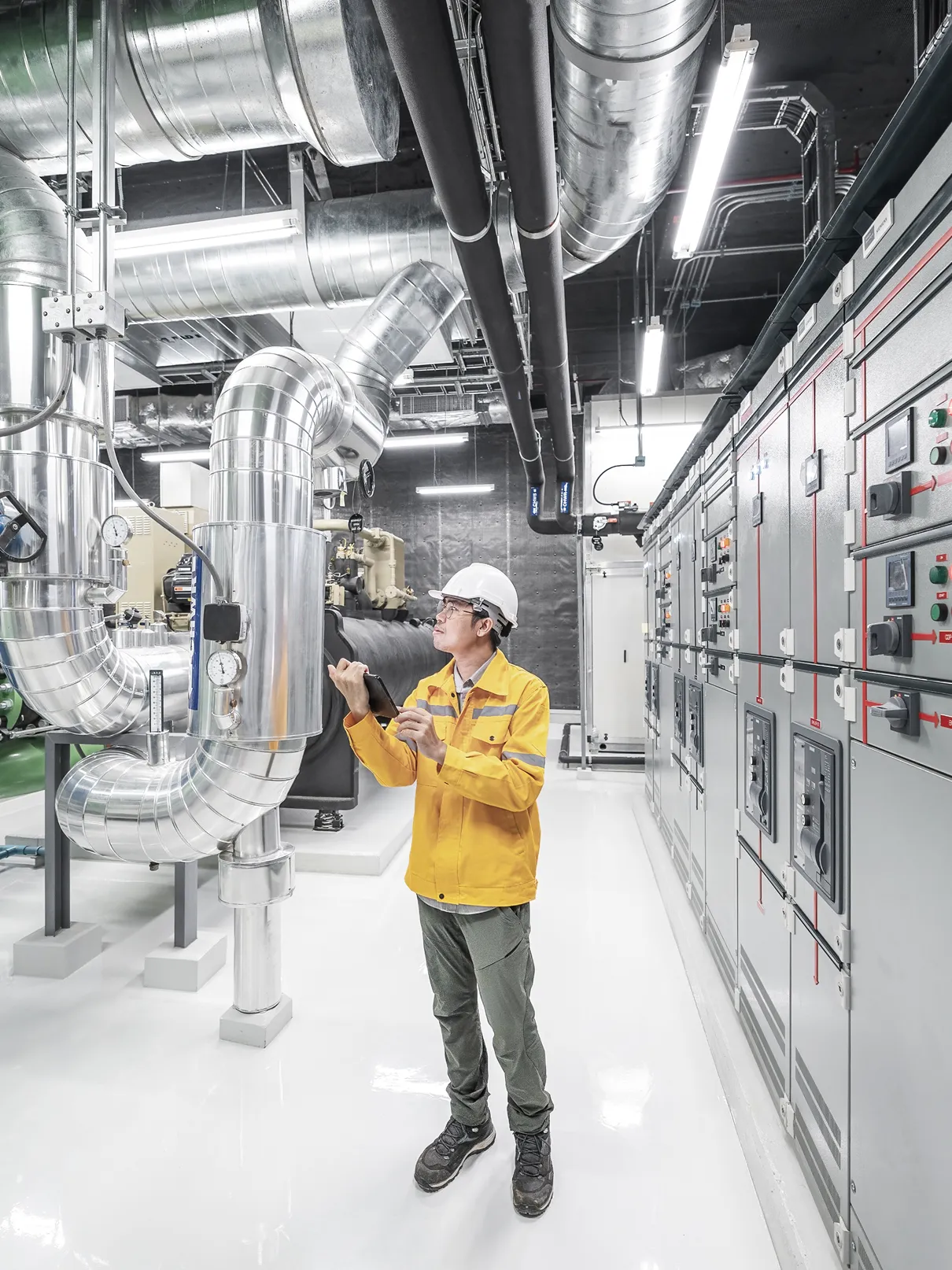 A man in a yellow jacket is standing in front of a large pipe. - Forgent Images