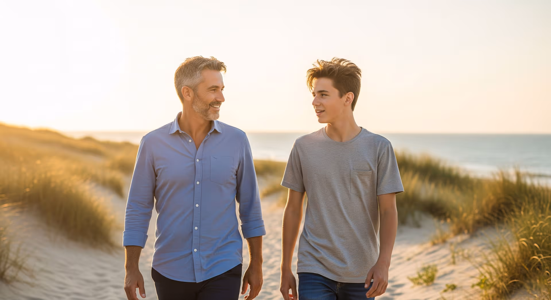 A man and his son walking on the beach.