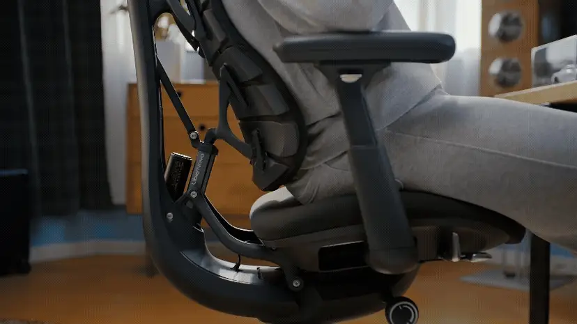 Person sitting on ergonomic office chair with detailed adjustable back support and armrest.