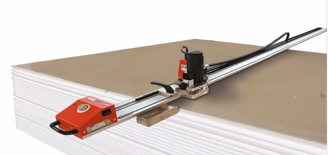 Long metal rail guiding a handheld cutting tool positioned over a stack of white foam boards with a brown top layer.