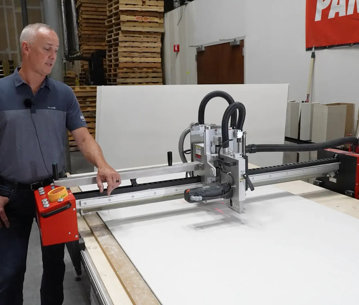 Man operating a large CNC machine used for cutting or shaping materials in an industrial workshop.
