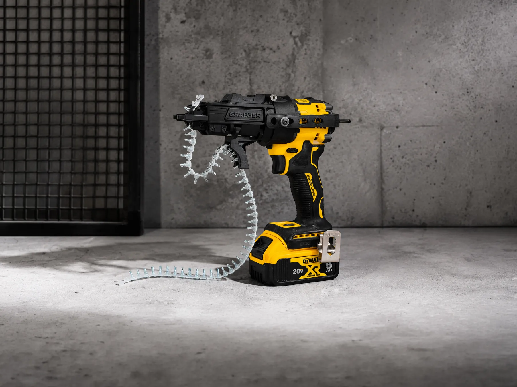 Yellow and black DEWALT 20V XR cordless nail gun with a coil of nails on a concrete floor.