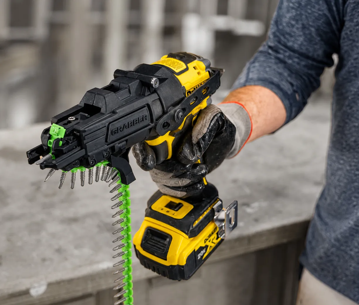 Person wearing gloves holding a yellow and black cordless collated screw gun with screws attached.