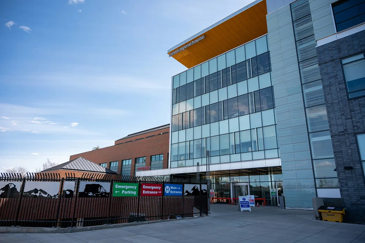 Glass-fronted hospital building with emergency entrance signage