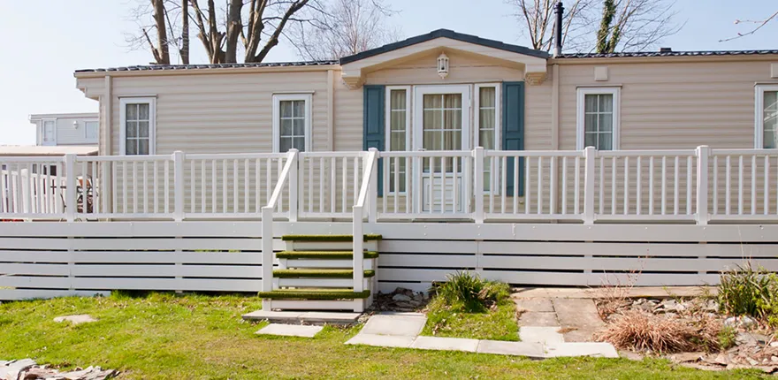 Beige mobile home with a white porch and railing