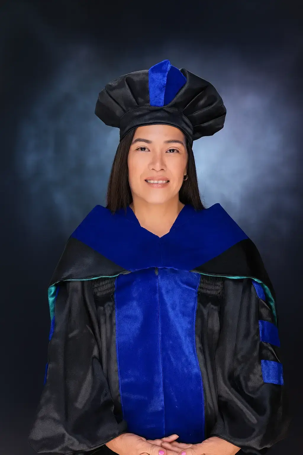 Woman in doctoral regalia and cap smiling for portrait
