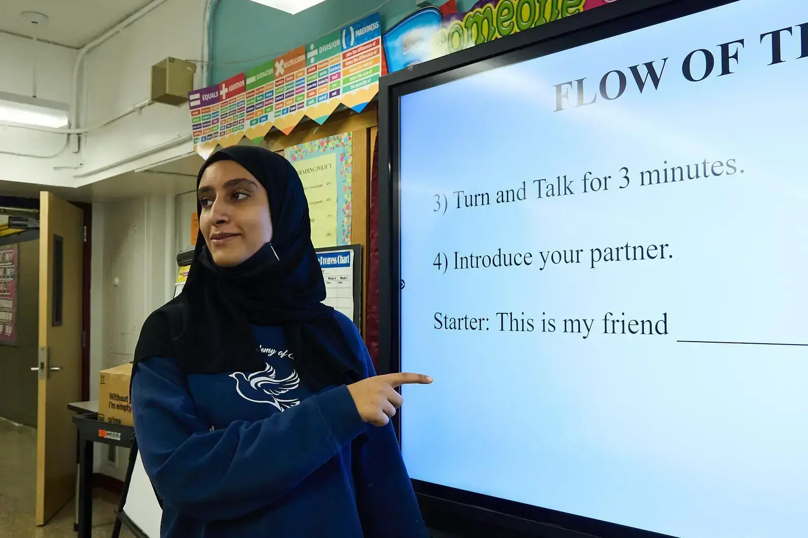 Student pointing to classroom smartboard displaying discussion instructions
