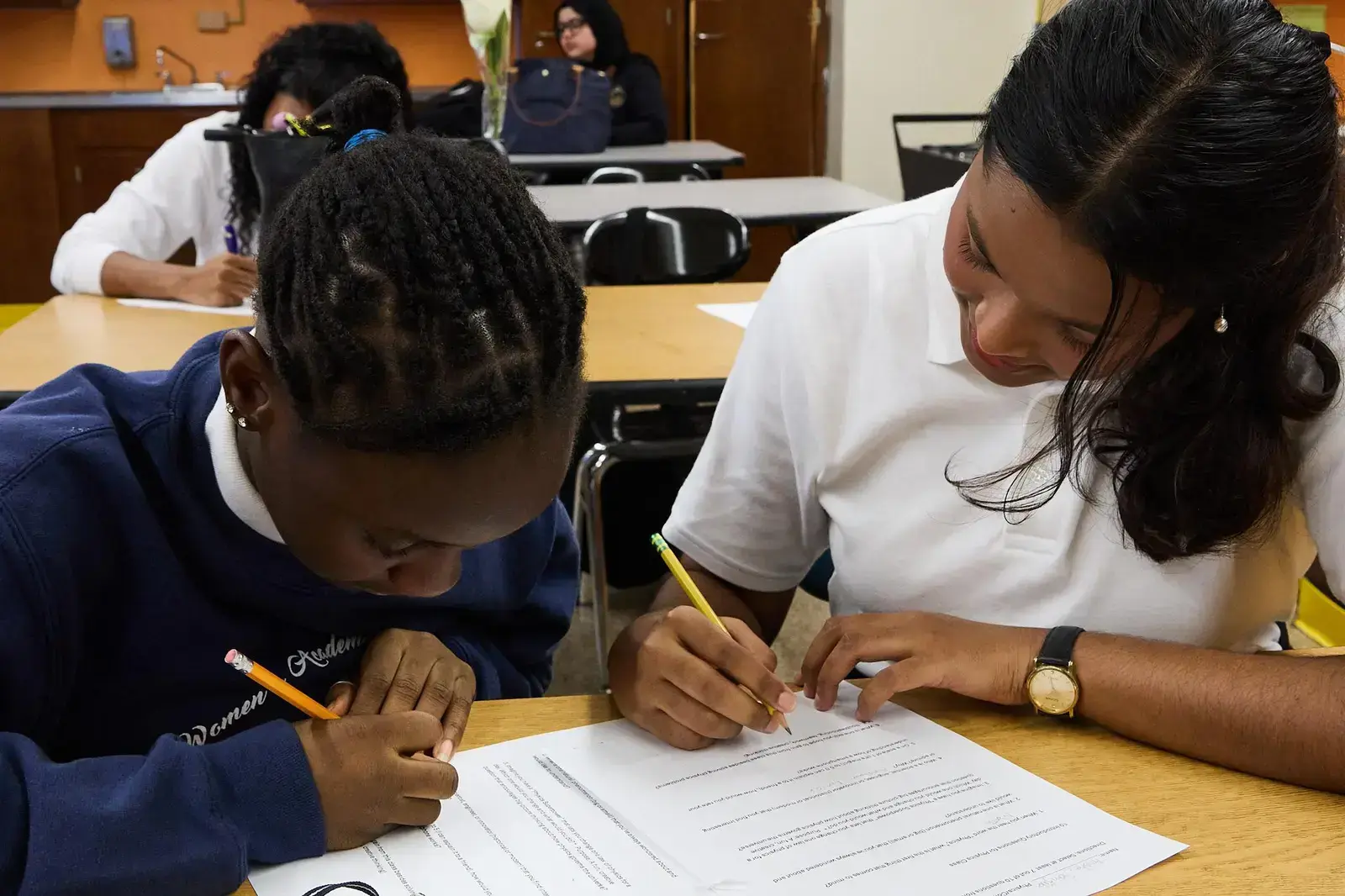 Two students working together on a written assignment at a desk
