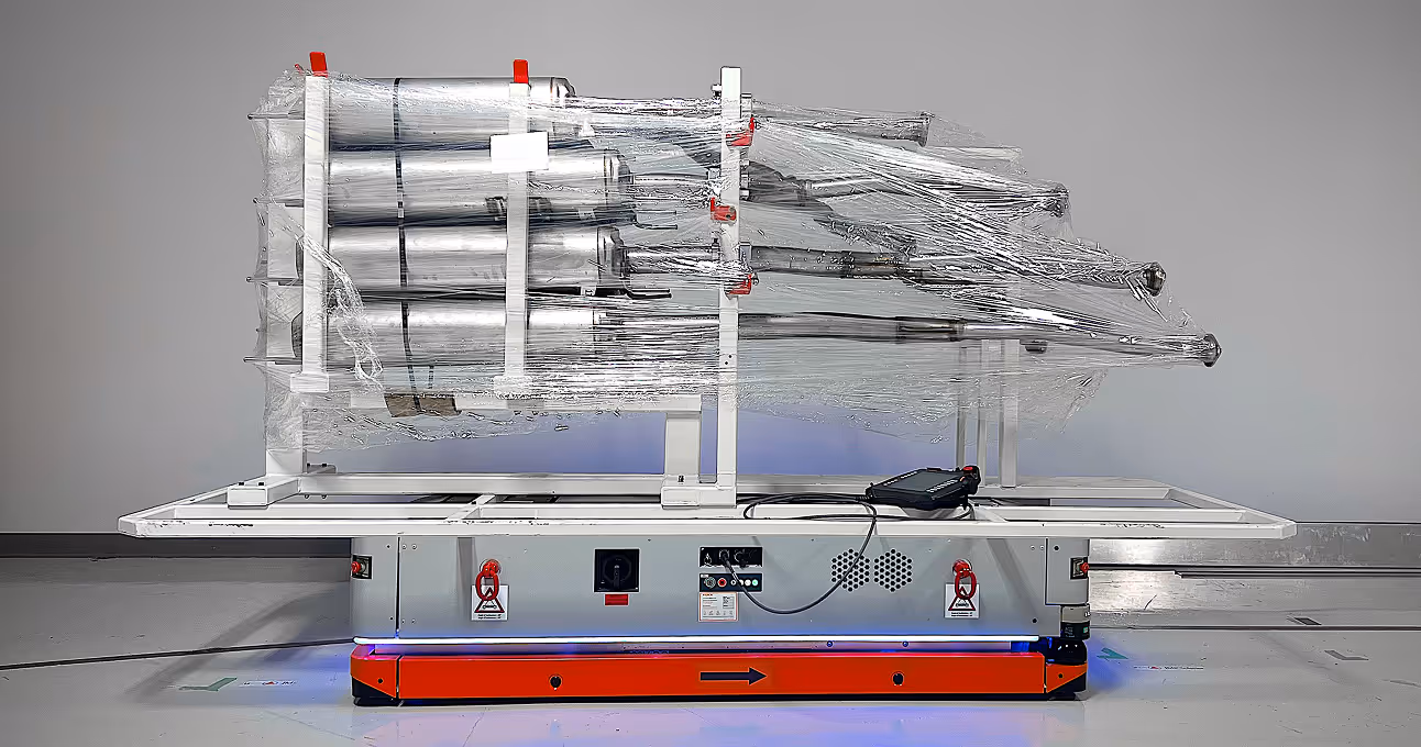 Automated guided vehicle carrying wrapped cylindrical metal parts in a warehouse.