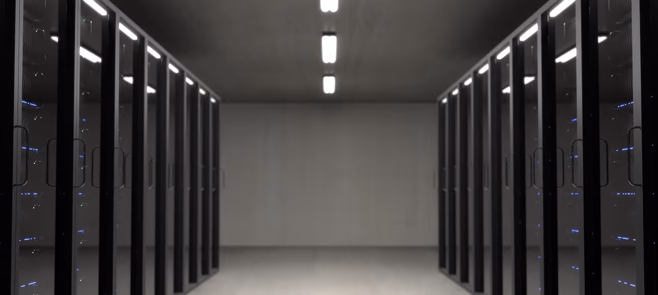 Empty aisle between two rows of black server racks inside a data center with ceiling lights.