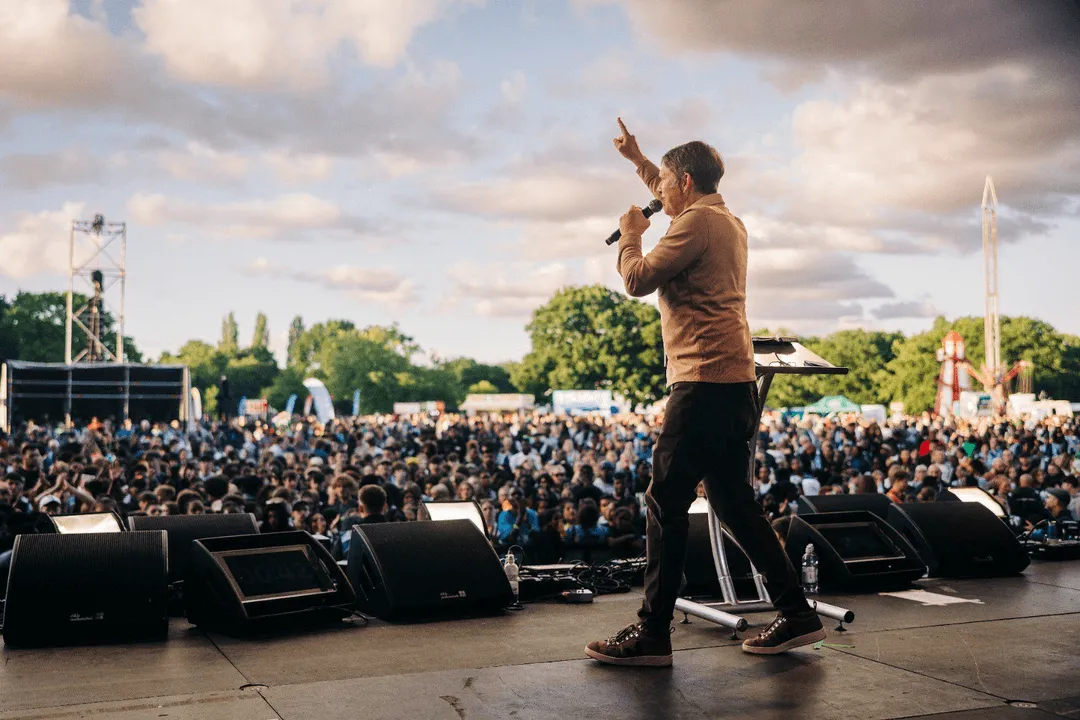 Andrew Palau speaking to a crowd of people while walking across the stage 