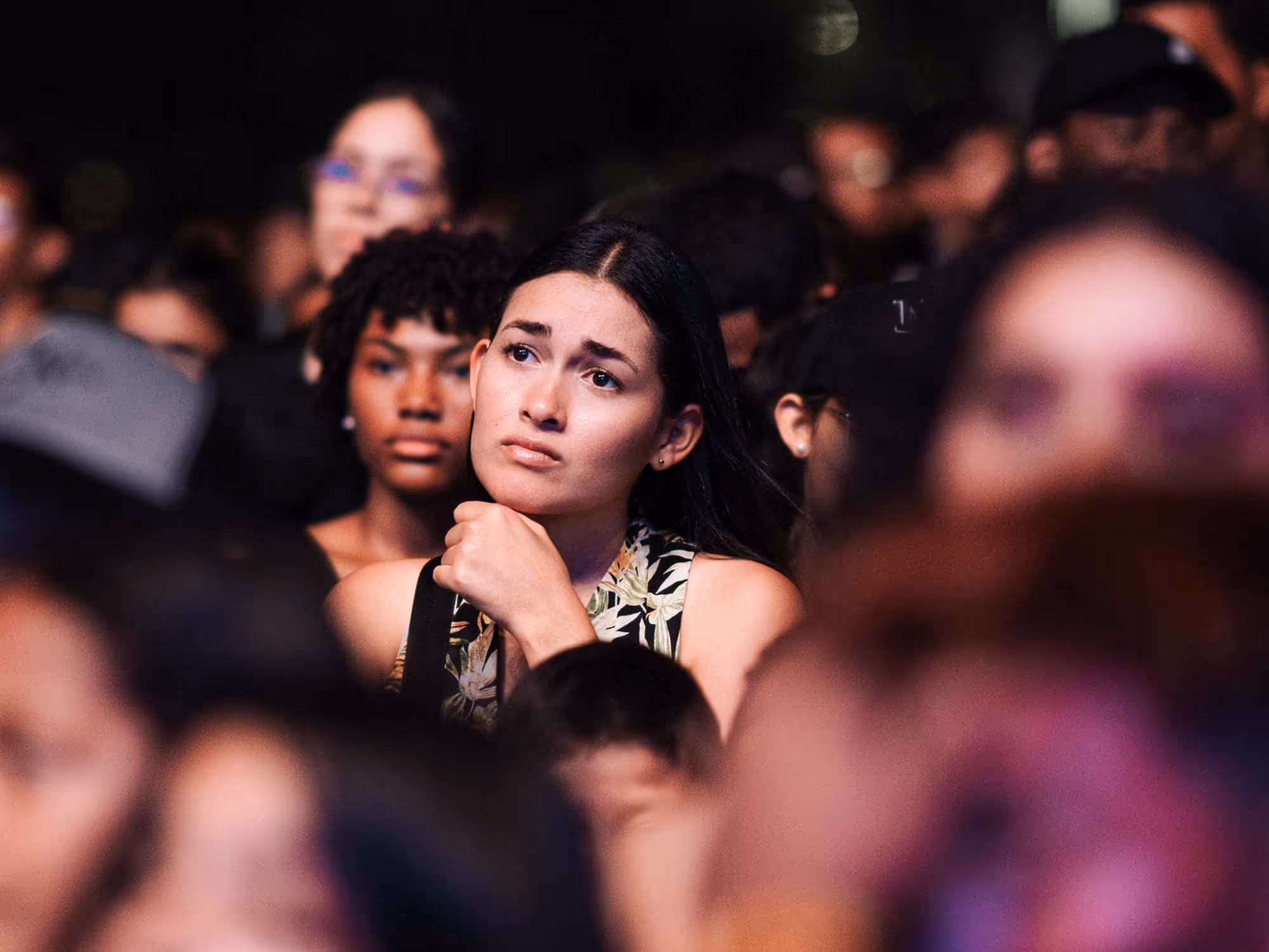 Woman in a crowd gazing into the distance with emotional expression