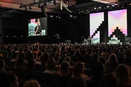 A person on stage speaking to a crowd of people
