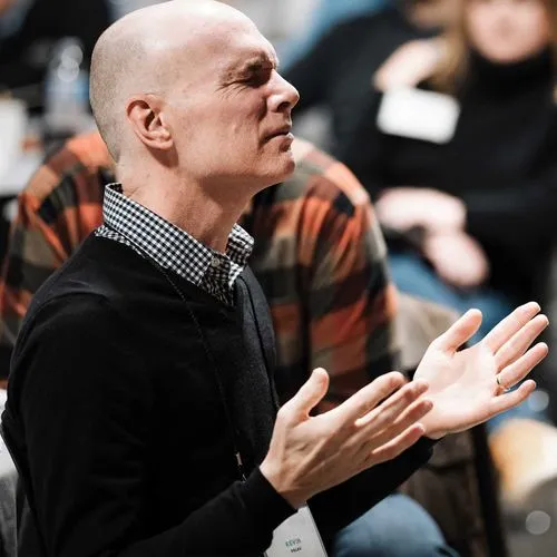 Kevin Palau with his eyes closed and his hands open in prayer