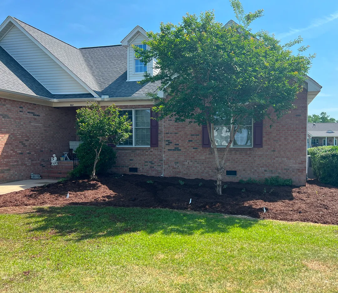 An exterior of a brick home with a mulched garden bed in front by the Walston Evans landscaping services