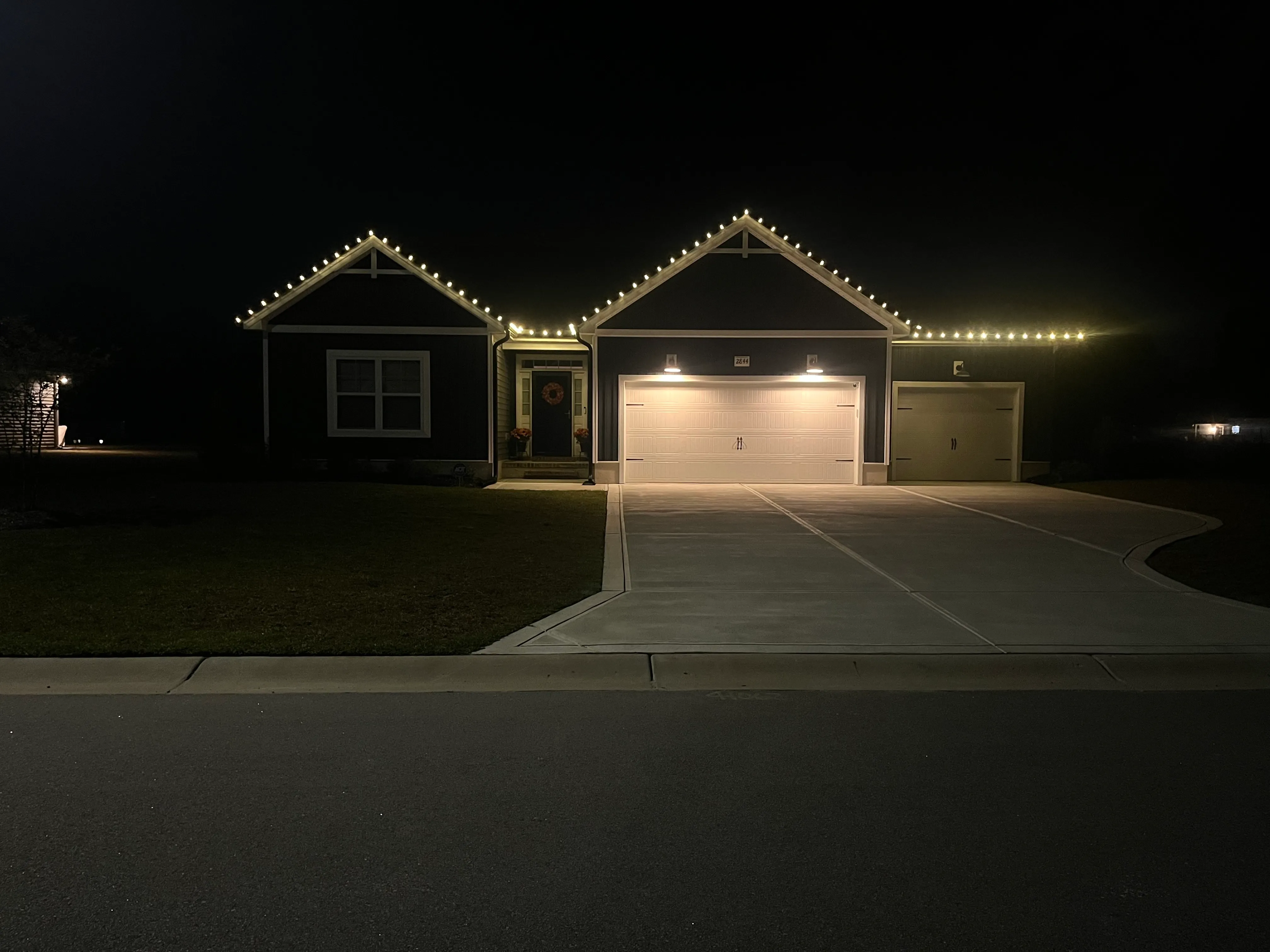 A beautiful home in the dark at night, shining bright with Christmas lights