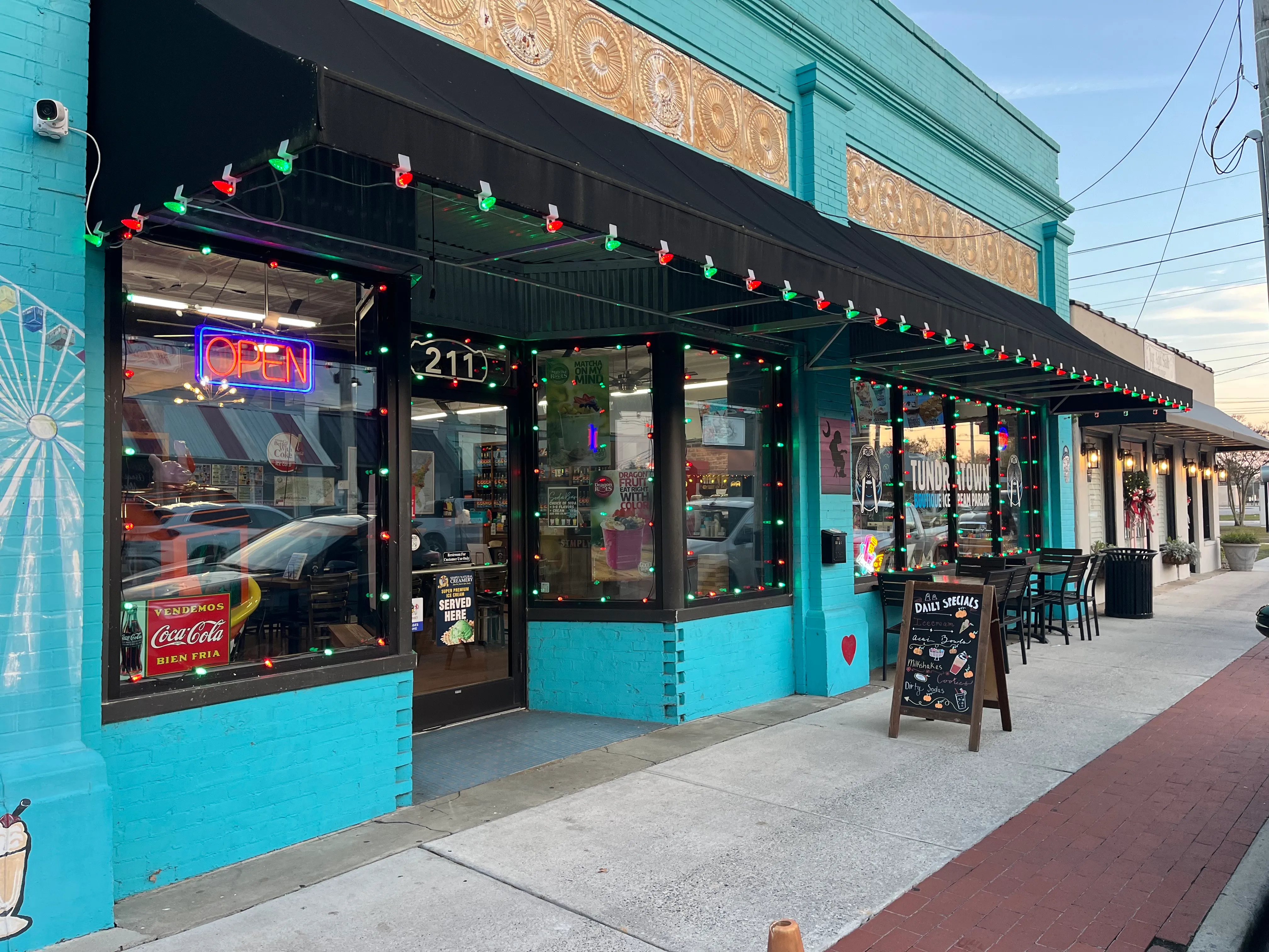 A storefront that is festively decorated for Christmas with Christmas lights and other Christmas decor
