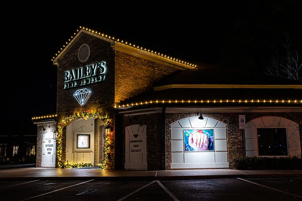 Bailey's Fine Jewelry store at night with lit holiday decorations outlining the building and a glowing diamond sign above the entrance.