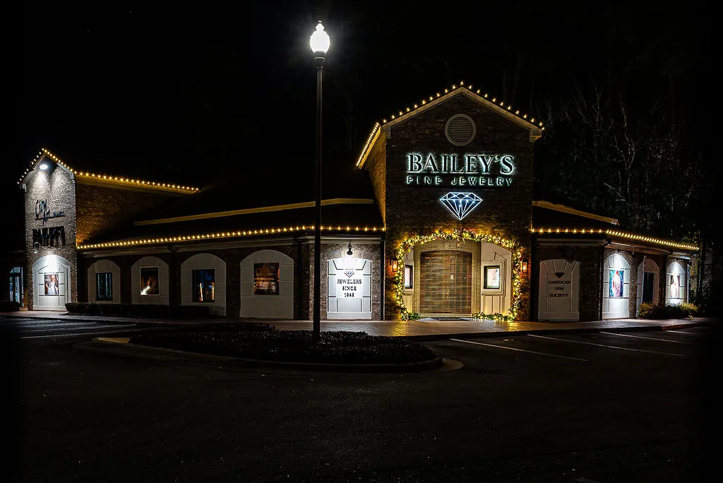 Bailey's Fine Jewelry store building at night with illuminated signage and decorative holiday lights outlining the roof and doorway.
