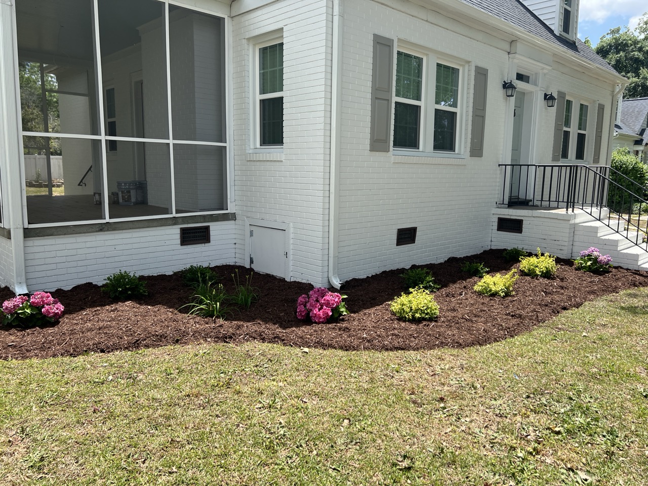 the exterior of a home with a nice mulch bed and planted flowers by Walston Evans