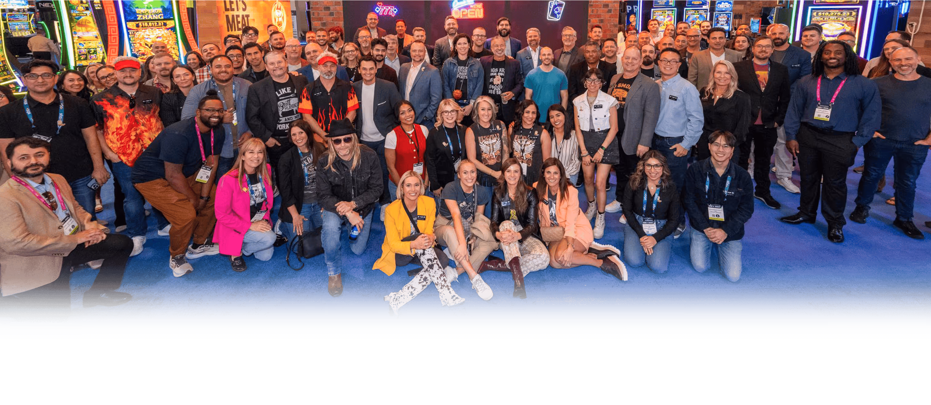 Large group photo of conference attendees in casino setting with colorful backdrop