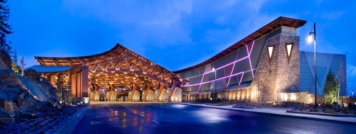 Close-up of an illuminated slot machine's green-lit spin button with colorful game symbols and amounts visible nearby.