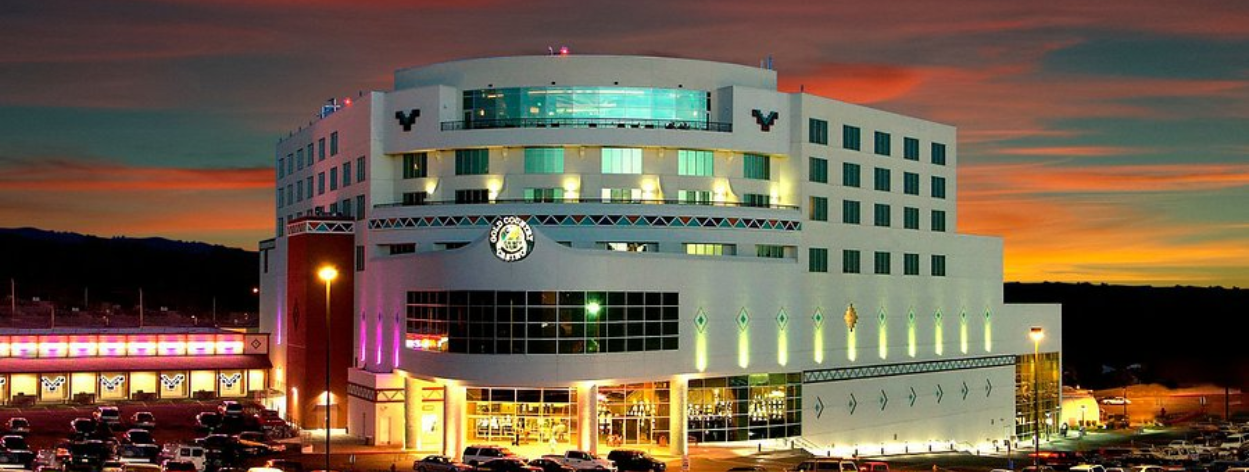 Close-up of an illuminated slot machine's green-lit spin button with colorful game symbols and amounts visible nearby.