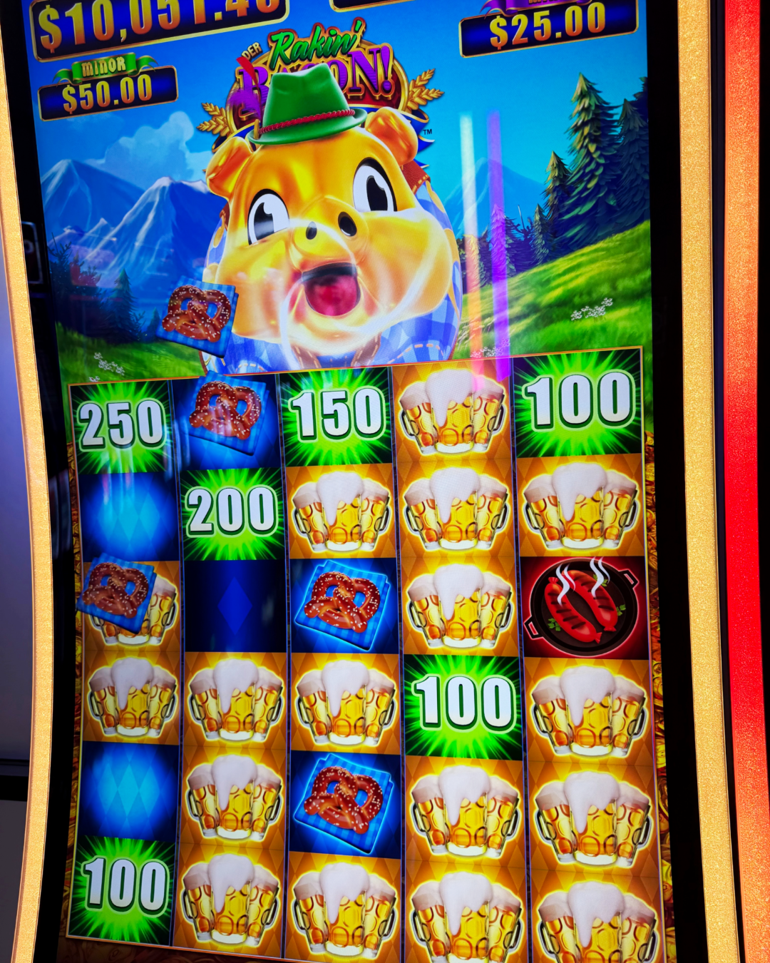 A woman holding a microphone stands next to a brightly lit slot machine featuring a werewolf design at a gaming convention.