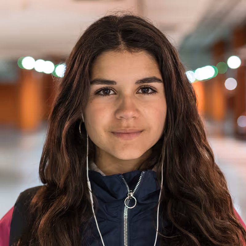 Portrait photo of young girl with earphones inside a school corridor. Stock photo. Posed by model.