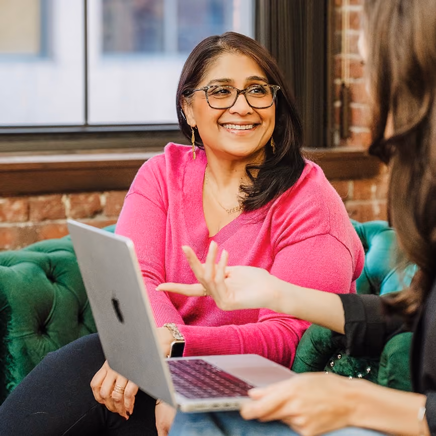 Two MHJP team members sitting on green couches and having a conversation. 