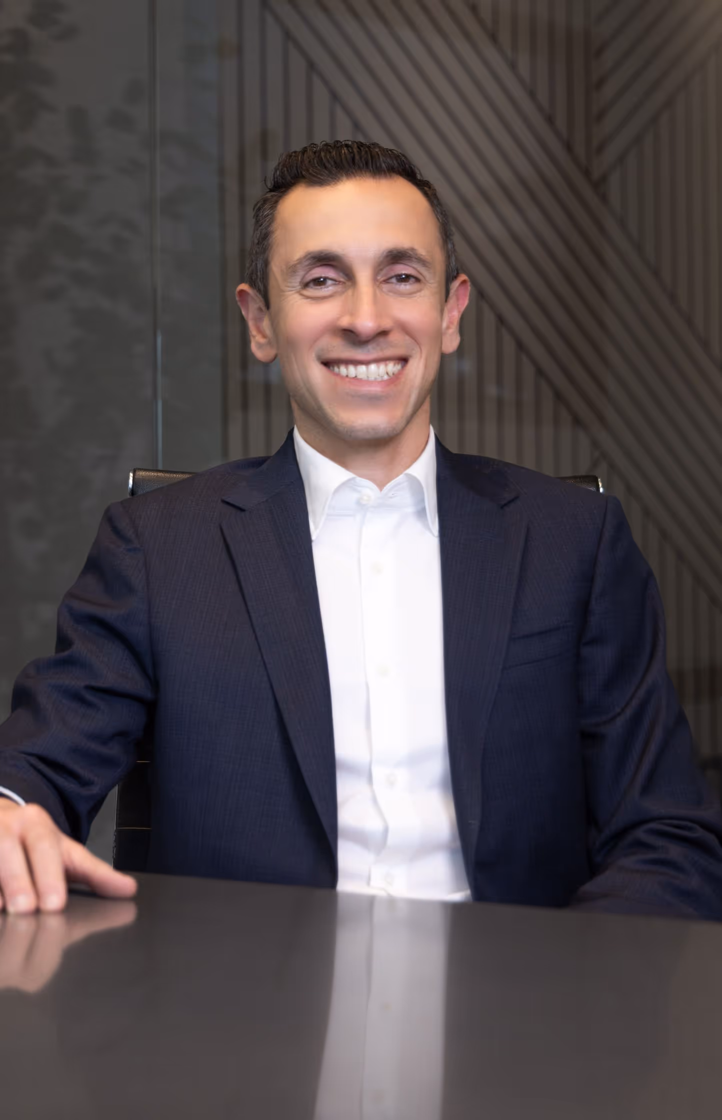 Headshot of Dr. Basseri in a dark suit smiling at the camera at his office in Beverly Hills.