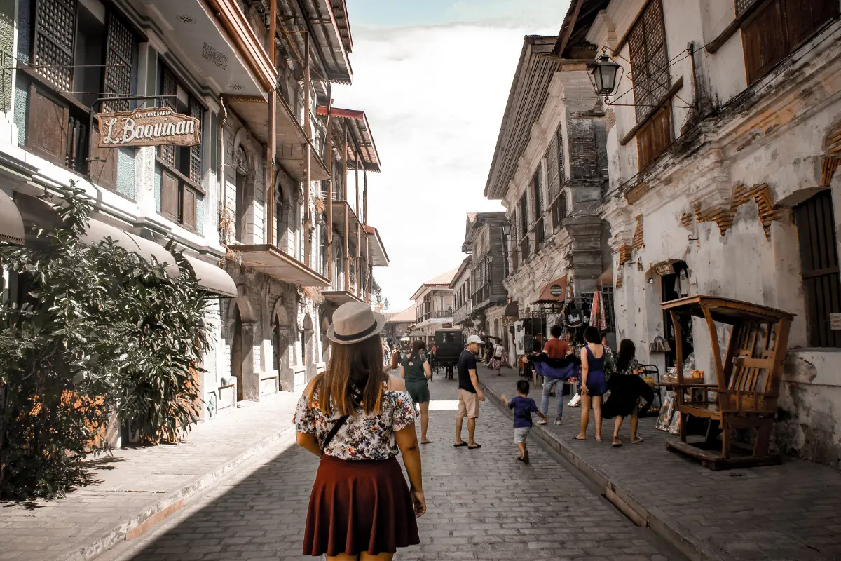 A traveler exploring a historic cobblestone street lined with old buildings and local shops.