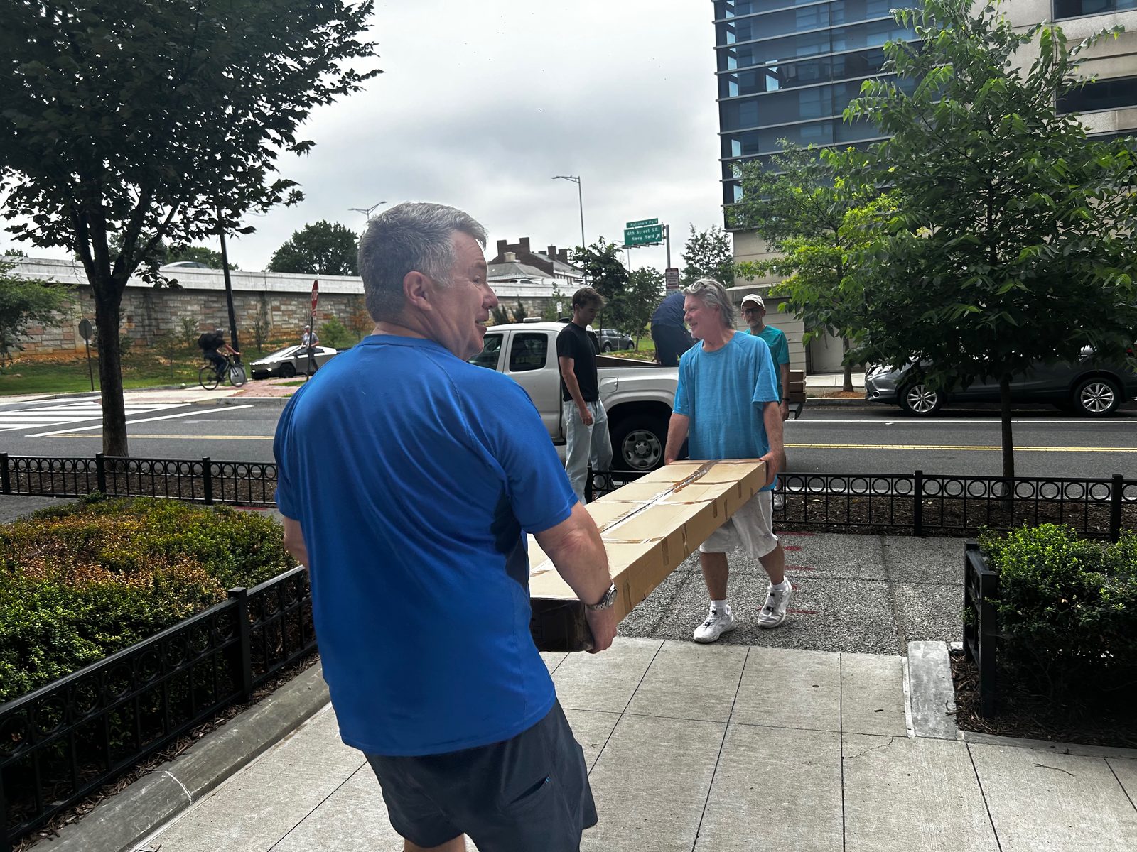 Volunteers carrying a long net box along the sidewalk to the new courts