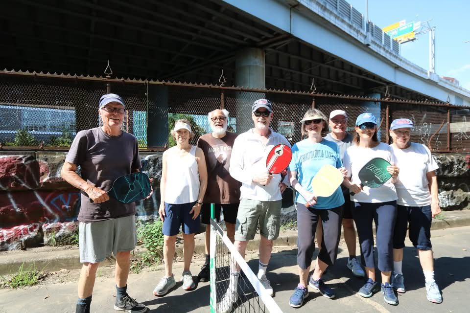 About a dozen of the original Garfield Park players with their paddles, under the freeway