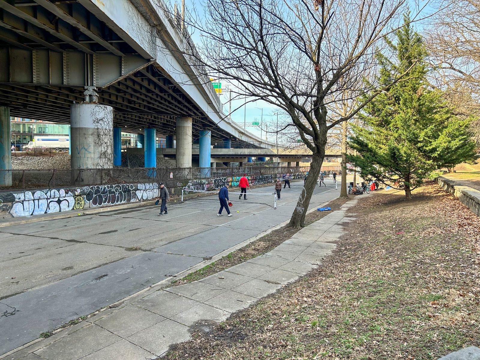 Players on the bare asphalt roadway under the freeway, before the Krughoff courts were built
