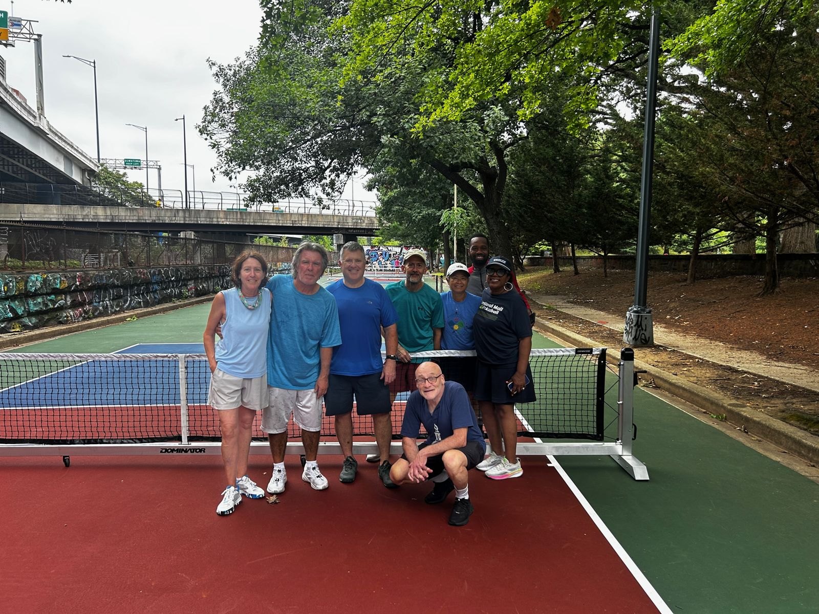Ten volunteers posing on a red court beside a newly installed net
